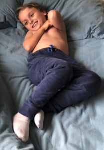 A child lies on a bed with their hips, elbows, and knees all facing different directions