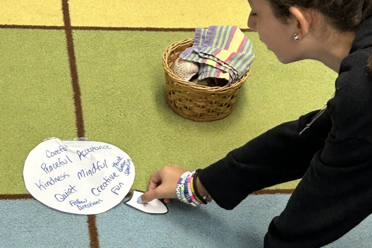 A pale-skinned woman in her mid-twenties draws on a mat