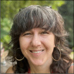 A white woman smiling with brown and grey hair