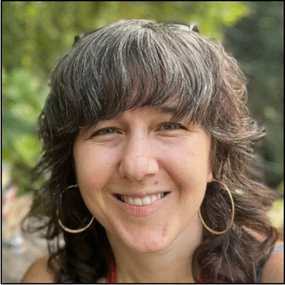 A white woman smiling with brown and grey hair