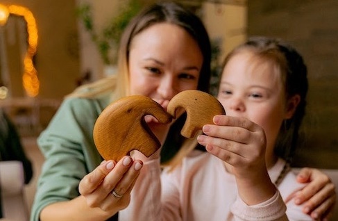 A woman and a child with Down Syndrome work on a puzzle together