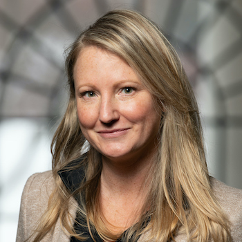 A pale-skinned blonde woman in her mid-forties with hair worn loose to her shoulders, wearing a blazer