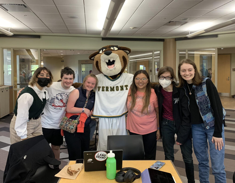 A group of college-aged students with their arms around a mascot in a Catamount suit