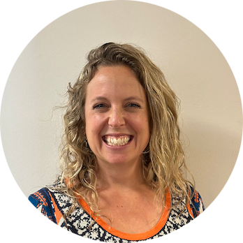 A white woman in her mid-thirties with curly blonde hair worn loose to her shoulders, smiling happily at the camera