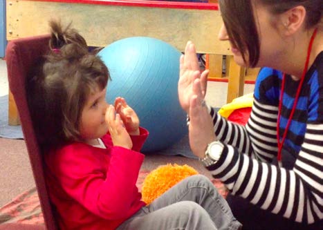 Figure 2c. The young girl and her intervener continue in the same position on the floor
and move their hands away from each other. The girl looks at the intervener, smiles, and
moves her hands closer to the intervener to indicate that she wants to continue the
game.