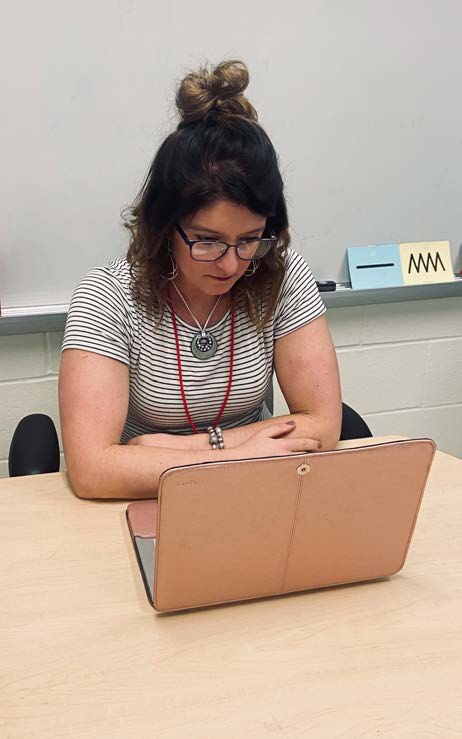 Figure 12a. A special educator is sitting at a table watching a video on her laptop of
herself interacting with a student. The expression on her face shows she is thinking
about her interaction with her student and learning from it. She can see things the
student may be communicating that she could not see during the
interaction in the moment. Perhaps she can use the insight to improve her next
interaction with this student.