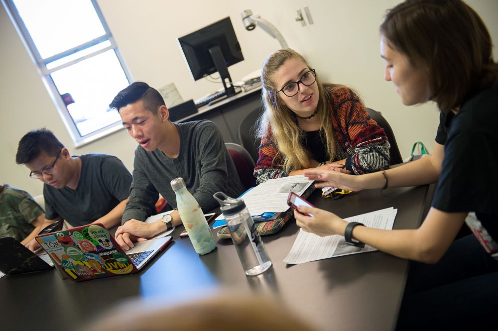 People sitting around a table talking and reviewing notes